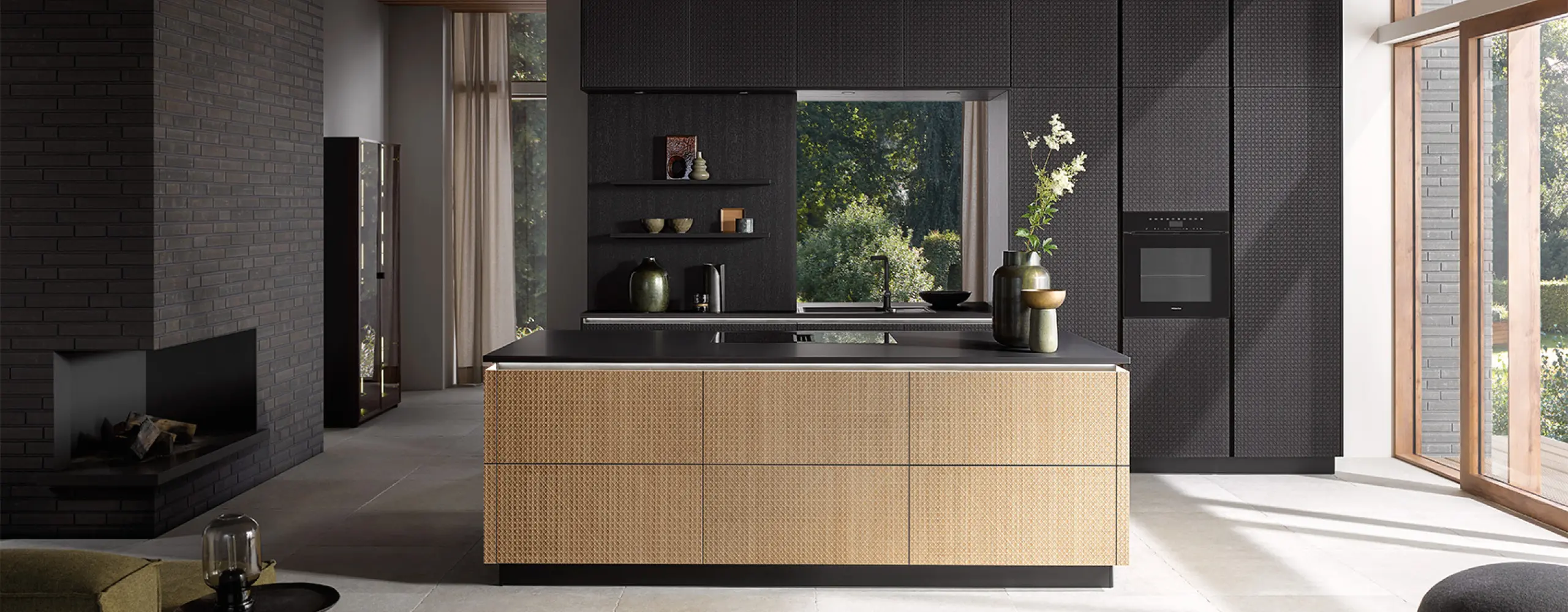 Edle Küche in Schwarz mit Rattan-Optik an der Kochinsel. Kombination aus dunklen Fronten, Holzdetails und großen Fenstern sorgt für luxuriöse Wohnatmosphäre und stilvolles Küchendesign.